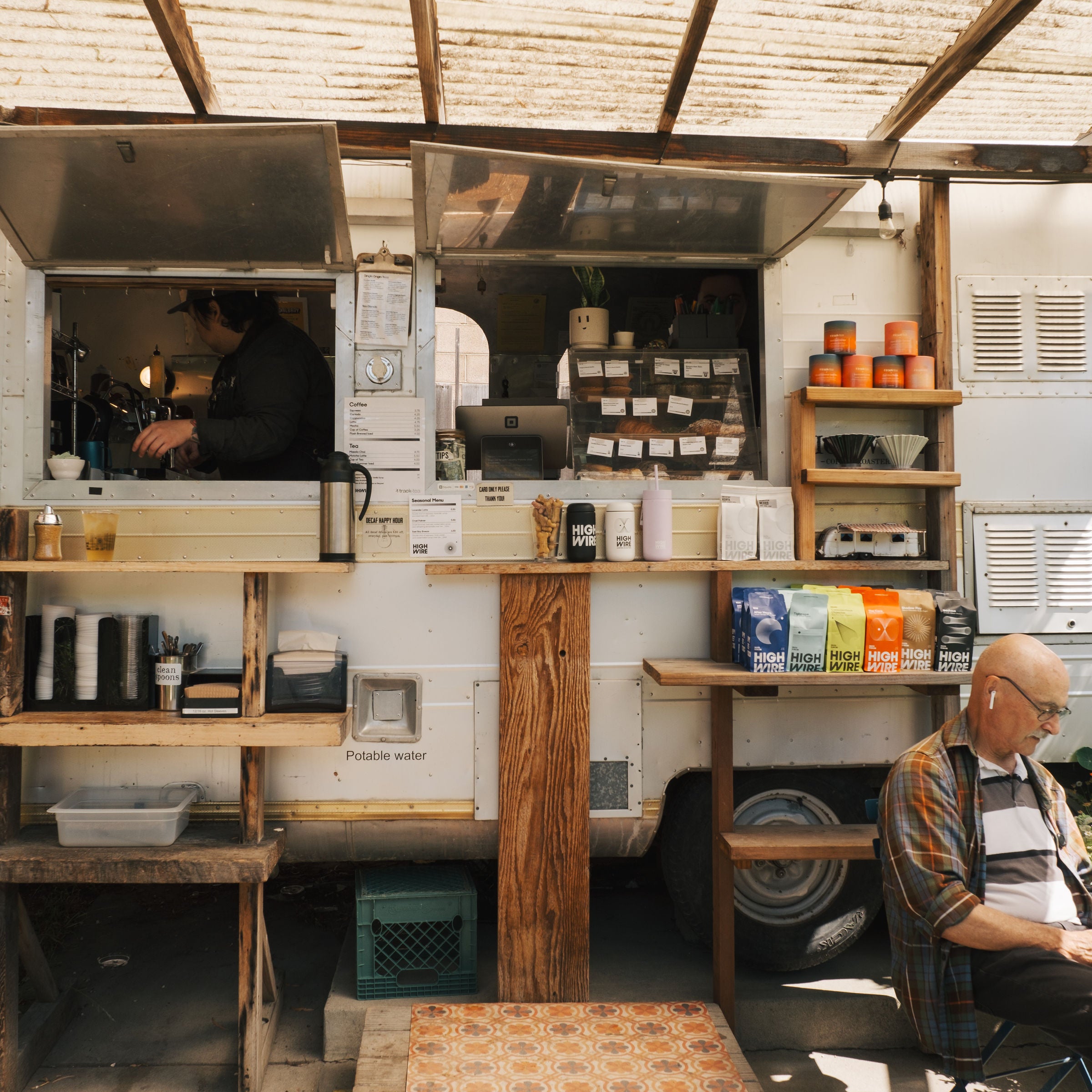 Highwire's coffee shop trailer in Flowerland. A customer enjoy's a drink at a nearby table.
