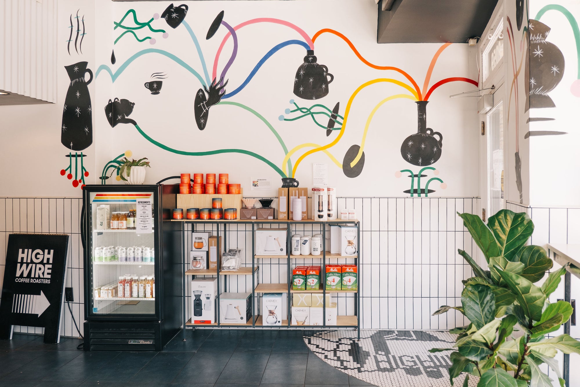Products on display in front of a colorful mural at Highwire's coffee shop in Montclair