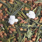 Close-up of green tea leaves with toasted rice grains and white popped rice on a textured background